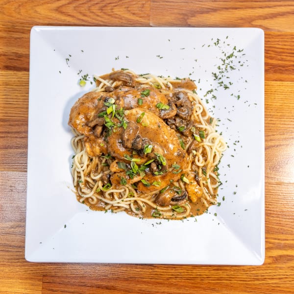 Chicken and mushroom pasta with a creamy sauce, garnished with green onions and parsley.