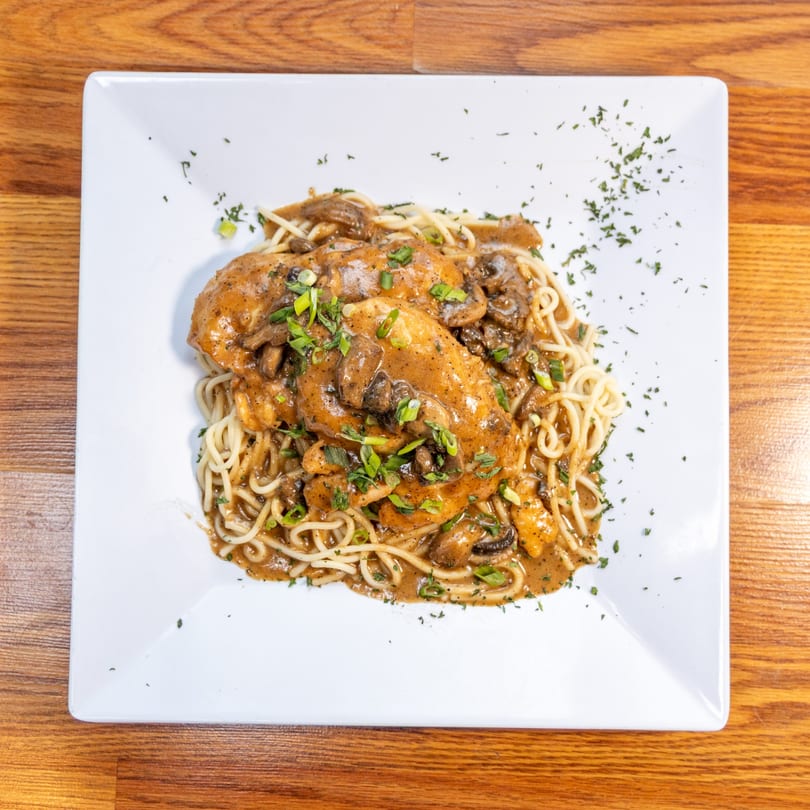 Chicken and mushroom pasta with a creamy sauce, garnished with green onions and parsley.